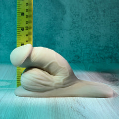 Gender X 4-inch packer laid beside a ruler showing approximate height on teal background