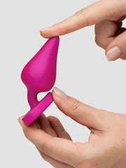 Hand flexing the soft silicone base of the pink ROMP Luster plug showing material flexibility