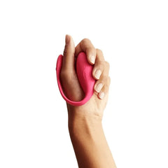 Hand gently gripping the We-Vibe Jive electric pink vibrator, showing its compact palm-sized form