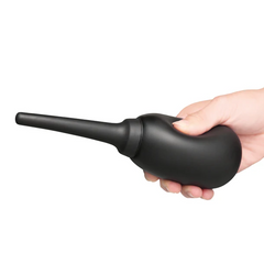 Hand gripping black silicone anal douche horizontally, showing ergonomic bulb size