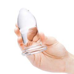 Hand gripping largest clear glass dilator, demonstrating substantial size and weighted feel