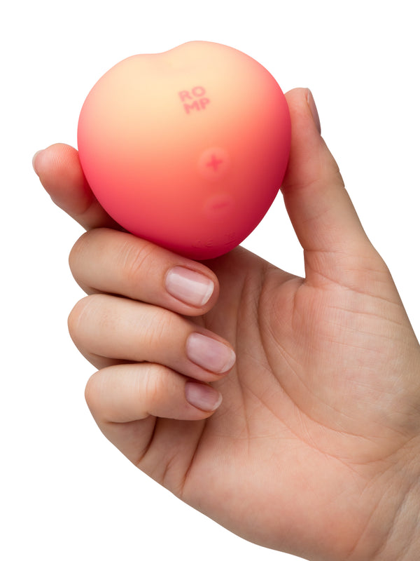 Hand gripping the ROMP Pink Peach to illustrate its palm-sized ergonomic form factor