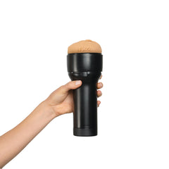 Hand holding assembled Kiiroo FeelAgatha Vega stroker showing black case with skin-tone sleeve inserted