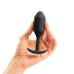 Hand holding b-Vibe Snug Plug 2 black silicone plug to show compact, palm-fitting size