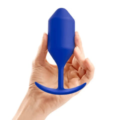 Hand holding b-Vibe Snug Plug 4 navy blue silicone plug to illustrate size and tapered shape