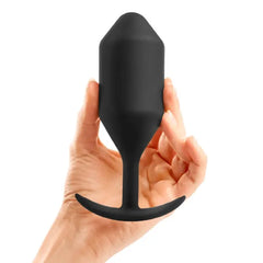 Hand holding b-Vibe Snug Plug 5 black silicone weighted anal plug to illustrate size and scale
