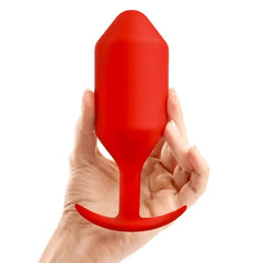 Hand holding b-Vibe Snug Plug 6 red silicone plug to illustrate its large size and weight