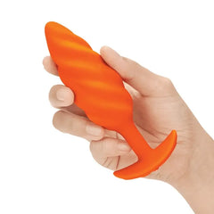 Hand holding the b-Vibe Swirl orange textured plug to show size and soft silicone feel