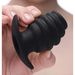 Hand holding black ribbed silicone hollow anal plug to show size and flexible material