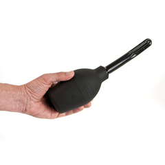 Hand holding the black silicone anal douche, showing compact squeeze-bulb size