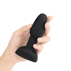 Hand holding black silicone rimming plug petite showing compact, palm-sized scale