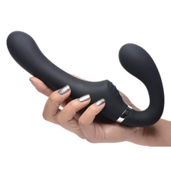 Hand holding black silicone strapless strap-on showing curved dual-end shape and textured grip zone