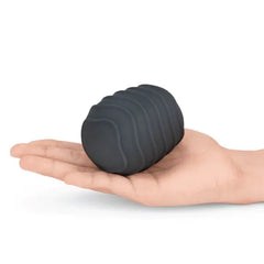 Hand holding a charcoal wave-textured silicone cover, showing compact oval size and ribbed detail