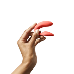 Hand holding the compact coral Chorus couples vibrator to show ergonomic size and fit