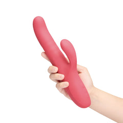 Hand holding coral pink Le Wand Thrust rabbit vibrator upright to show size and ergonomic grip