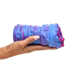 Hand holding Cyclone squishy silicone stroker showing compact size and marbled blue-purple exterior