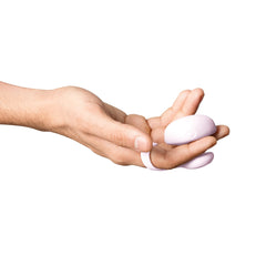 Hand holding Dame Fin 2.0 pink finger vibrator, showing compact palm-sized fit