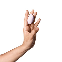 Hand holding Dame Fin 2.0 upright between fingers, showing slim egg-shaped profile