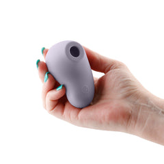 Hand holding the Desire Tresor dusk purple silicone stimulator showing compact size