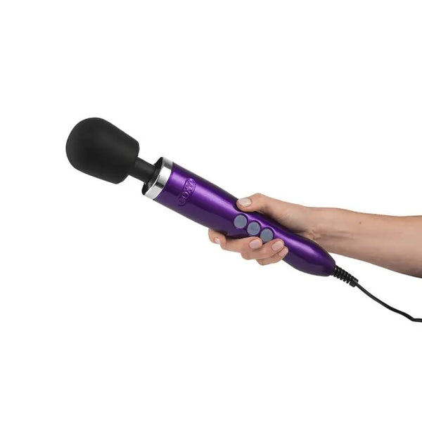 Hand holding the Doxy Die Cast wand massager, showing ergonomic grip size and purple metallic handle