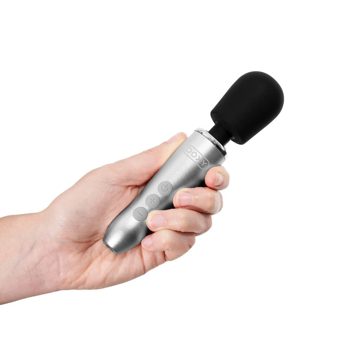 Hand holding the Doxy Go compact wand vibrator, showing silver handle and black silicone head