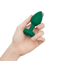 Hand holding emerald green b-Vibe silicone anal plug to show compact size