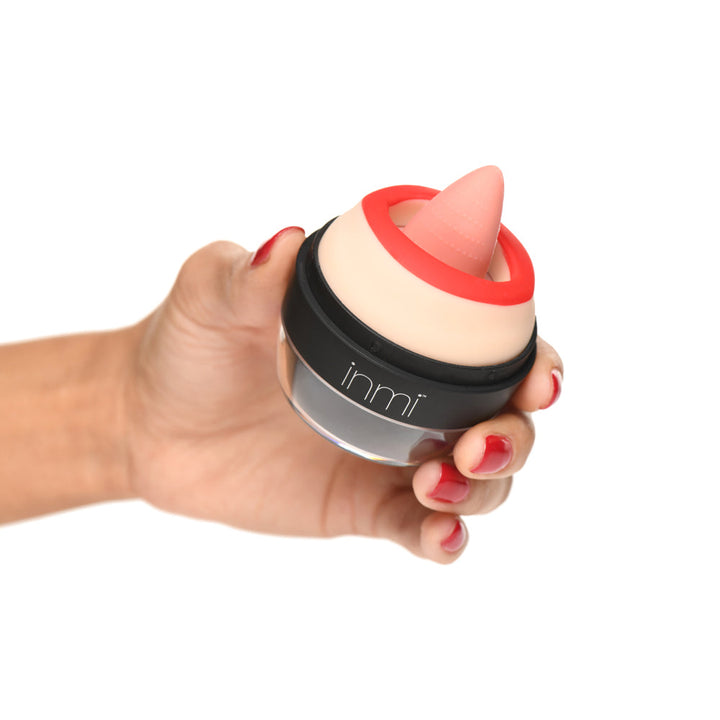 Hand holding the Inmi Lady Licker oral stimulator with soft tongue tip and red lip ring visible