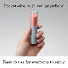 Hand holding Iroha coral and gray stick vibrator showing compact lipstick-style size