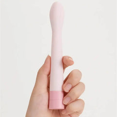Hand holding Iroha Koharu vibrator in blush pink colorway showing slim handle size