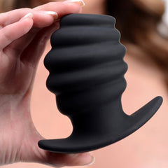 Hand holding the large black Master Series Hive Ass Tunnel plug, showing ribbed texture and flared base