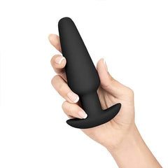 Hand holding large black silicone anal plug illustrating graduated size progression in the training set