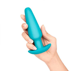 Hand holding large teal silicone plug showing smooth matte finish and secure flared anchor base