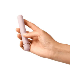 Hand holding Le Wand Baton slim pink vibrator showing compact travel-friendly size