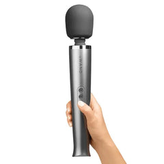 Hand holding the Le Wand grey silicone head massager upright showing ergonomic grip and button placement