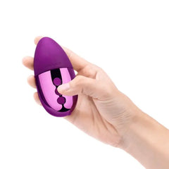 Hand holding the Le Wand Point mini vibrator showing compact palm-friendly size and button placement