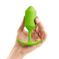 Hand holding lime green b-Vibe Snug Plug 3 demonstrating compact insertable size
