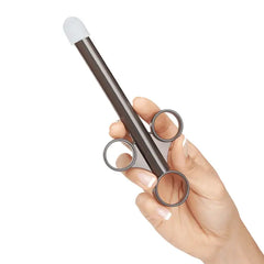 Hand holding loaded black lubricant applicator showing plunger tip extended for use