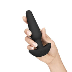 Hand holding medium black silicone anal plug displaying b-Vibe logo on base and sleek matte finish