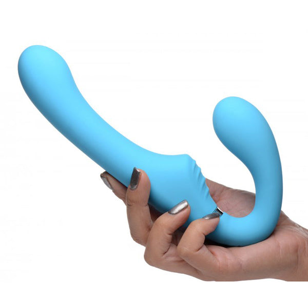 Hand holding the Mighty Rider strapless strap-on in soft blue premium silicone, showing dual-end curved shape