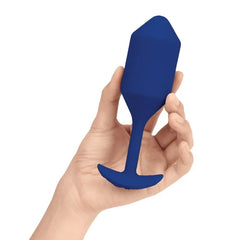 Hand holding navy b-Vibe Snug Plug 4 to show scale — fits comfortably in one hand