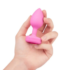 Hand holding pink silicone plug to show compact size and power button on base