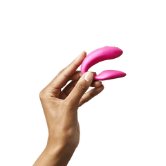 Hand holding pink We-Vibe Chorus couples vibrator to show compact, flexible two-arm size