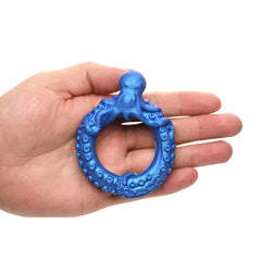 Hand holding Poseidon's Octo-Ring to show compact palm-sized scale of the blue silicone ring