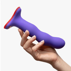 Hand holding purple Fun Factory Bouncer dildo horizontally, showing slim tapered base and ribbed texture