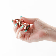Hand holding the Rear Assets Petite rose gold plug, showing its compact petite size
