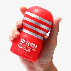 Hand holding the red SD Tenga Original Vacuum Cup to show its compact, palm-sized fit
