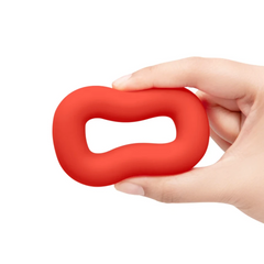 Hand holding red silicone cock ring, demonstrating flexible, squeezable material