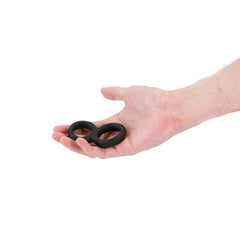 Hand holding the Renegade Twofold dual cock ring, showing its compact, palm-sized scale
