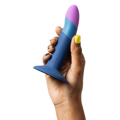 Hand holding ROMP Piccolo dildo showing smooth tri-tone silicone finish and suction base