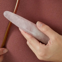 Hand holding a rose quartz Chakrubs crystal dildo, showing its smooth polished length